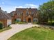 Brick house with a circular driveway, lush green lawn, and manicured landscaping at 9501 Tavistock Rd, Orlando, FL 32827