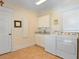 Well-lit laundry room with modern washer, dryer, and ample cabinet space at 9501 Tavistock Rd, Orlando, FL 32827