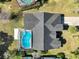 Aerial view of the home showing the roof, driveway, screened-in pool, and surrounding yard at 10012 Silver Bluff Dr, Leesburg, FL 34788