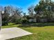 Spacious backyard featuring lush green grass, a concrete patio, mature trees, and a privacy fence at 10012 Silver Bluff Dr, Leesburg, FL 34788
