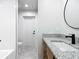 Bathroom featuring a wood vanity, granite countertop, round mirror, and door to the shower at 10012 Silver Bluff Dr, Leesburg, FL 34788