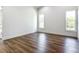 Empty bedroom with wood floors, white trim and walls, and two windows letting in lots of natural light at 10012 Silver Bluff Dr, Leesburg, FL 34788