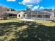Home exterior view showcasing a large, screened-in pool and spacious green yard at 10012 Silver Bluff Dr, Leesburg, FL 34788