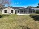 Home exterior view showcasing a large, screened-in pool and spacious green yard at 10012 Silver Bluff Dr, Leesburg, FL 34788