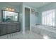 Relaxing bathroom showcasing a marble-trimmed tub and a vanity with granite countertops at 15672 Shorebird Ln, Winter Garden, FL 34787