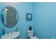 Stylish half-bathroom with blue walls, decorative mirror, and charming beach decor at 15672 Shorebird Ln, Winter Garden, FL 34787