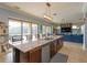 Kitchen island with seating and stainless steel dishwasher open to the living room with pool views at 15672 Shorebird Ln, Winter Garden, FL 34787