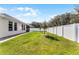 Backyard featuring a healthy green lawn, new white fence, and covered patio at 1598 Barberry Dr, Kissimmee, FL 34744