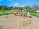 Aerial view of the community playground with swings and slides, surrounded by green grass and blue skies at 1598 Barberry Dr, Kissimmee, FL 34744