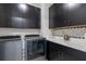 Modern laundry room features gray washer and dryer, dark cabinetry, and a stylish backsplash at 1763 Standing Rock Cir, Oakland, FL 34787