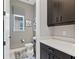 Stylish powder room with dark cabinets, quartz countertop, and window letting in natural light at 1763 Standing Rock Cir, Oakland, FL 34787