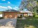 Charming brick home featuring a manicured lawn, attached two-car garage, and beautiful mature trees at 2031 Roseway Ave, Deltona, FL 32738