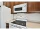 Close-up of the white stove, microwave and cabinets in the kitchen at 2136 Shadow Creek Dr, Kissimmee, FL 34746