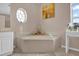 Bright bathroom showcasing a soaking tub with stylish fixtures and a decorative round window at 36525 Reserve Dr, Eustis, FL 32736