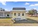 Exterior view of a small yellow house featuring a porch with a white door and windows at 36525 Reserve Dr, Eustis, FL 32736