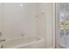 White bathtub with tiled walls, towel rack, and a view to the outside through a glass door at 3978 Old Dunn Rd, Apopka, FL 32712