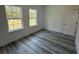 Bedroom featuring two windows offering natural light and gray wood flooring at 4650 Sw 139Th Pl, Ocala, FL 34473