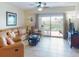 Bright living room with leather sofa, coastal decor, and sliding glass doors to a balcony at 5300 S Atlantic Ave # 6-206, New Smyrna Beach, FL 32169