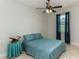 Bedroom with neutral tiled floors, a ceiling fan, a bed with blue bedding, and blue curtains at 619 Meadow Sage Dr, Deland, FL 32724