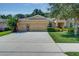 Home featuring a two-car garage, a paved driveway, and lush landscaping at 619 Meadow Sage Dr, Deland, FL 32724