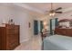 Bedroom with neutral tiled floors, a ceiling fan, a tray ceiling, blue curtains, and dark wood furniture at 619 Meadow Sage Dr, Deland, FL 32724
