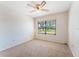A cozy carpeted bedroom featuring a ceiling fan and a view from the window overlooking the lawn at 6766 Edgeworth Dr, Orlando, FL 32819