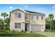 Two-story home featuring tan siding, a gray roof, attached two-car garage, and a manicured green lawn at 12910 Promise Pl, Orlando, FL 32832