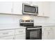 Stainless steel microwave and electric range, complemented by modern white cabinets and light countertops at 13283 Sw 30Th Terrace Rd, Ocala, FL 34473