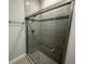 Modern bathroom shower with gray tile surround, glass doors, and sleek hardware fixtures at 13745 Sw 43Rd Cir, Ocala, FL 34473