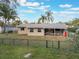 View of the backyard with a covered patio, set within a fenced yard with mature trees and a green lawn at 1456 Helena Ct, Deltona, FL 32725