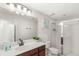 Bright bathroom with a walk-in shower, white countertop, dark wood vanity and stylish lighting at 1547 Carey Palm Cir, Kissimmee, FL 34747