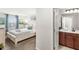 View of a bedroom with a queen bed, adjacent to a bathroom with a dark wood vanity and white countertop at 1547 Carey Palm Cir, Kissimmee, FL 34747