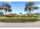 Community entrance with palm trees, water fountain, and lush landscaping under a blue sky at 1547 Carey Palm Cir, Kissimmee, FL 34747