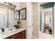 Neutral bathroom featuring a wood vanity, marble countertop, framed art and a decorative light fixture at 1990 Appalachee Cir, Tavares, FL 32778