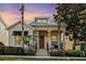 Charming home exterior with a metal roof, front porch, and manicured landscaping at dusk at 1990 Appalachee Cir, Tavares, FL 32778