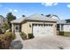 Attached two-car garage with carriage doors and a driveway paved with brick pavers at 1990 Appalachee Cir, Tavares, FL 32778