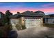 Garage with white carriage doors, brick-paved driveway and exterior coach lights at 1990 Appalachee Cir, Tavares, FL 32778