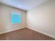 Neutral bedroom featuring a large window, beige carpeting, and multiple electrical outlets at 2687 Chantilly Ave, Kissimmee, FL 34741