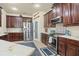 Well-lit kitchen featuring dark wood cabinets, stainless steel appliances, and modern tile backsplash at 2926 Falconhill Dr, Apopka, FL 32712