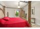 Elegant main bedroom showcases a carved four-poster bed with red quilted bedding and natural light at 2926 Falconhill Dr, Apopka, FL 32712