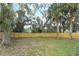 A fenced backyard featuring mature trees, manicured grass, and a wooden perimeter fence at 297 N Lake Jessup Ave, Oviedo, FL 32765