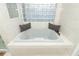 Well-lit bathroom with a large soaking tub, glass block window, and stylish pillows at 297 N Lake Jessup Ave, Oviedo, FL 32765