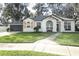 Charming single-story home with white brick, shutters, manicured lawn, and mature landscaping at 297 N Lake Jessup Ave, Oviedo, FL 32765