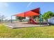 Shaded playground with a red canopy, slides, and play equipment on a sunny day at 400 Miami Way, Poinciana, FL 34759