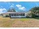 View of the back of the house with a screened-in porch, green lawn, and blue skies at 4520 Lake Gem Cir, Orlando, FL 32806