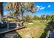 Backyard boasts a deck with stylish seating, a fire pit, and is shaded by mature trees draped in Spanish moss at 52 Bay Ridge Loop, Mascotte, FL 34753