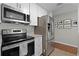 Contemporary kitchen featuring stainless steel appliances, white cabinets, and granite countertops at 52 Bay Ridge Loop, Mascotte, FL 34753