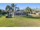 Exterior view of a home featuring an enclosed patio, large yard, and mature palm trees at 642 Osprey Lakes Cir, Chuluota, FL 32766