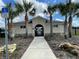 Exterior of a clubhouse with a sidewalk, landscaping, and nearby palm trees at 777 Orchid Grove Blvd, Davenport, FL 33837