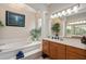 Bright bathroom features a soaking tub with white marble steps and a cherry wood vanity at 932 Classic View Dr, Auburndale, FL 33823